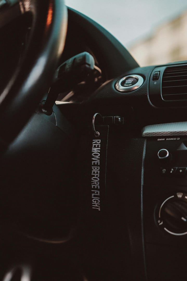 Close-up of a luxury car dashboard featuring a 'Remove Before Flight' keychain, highlighting elegant design.